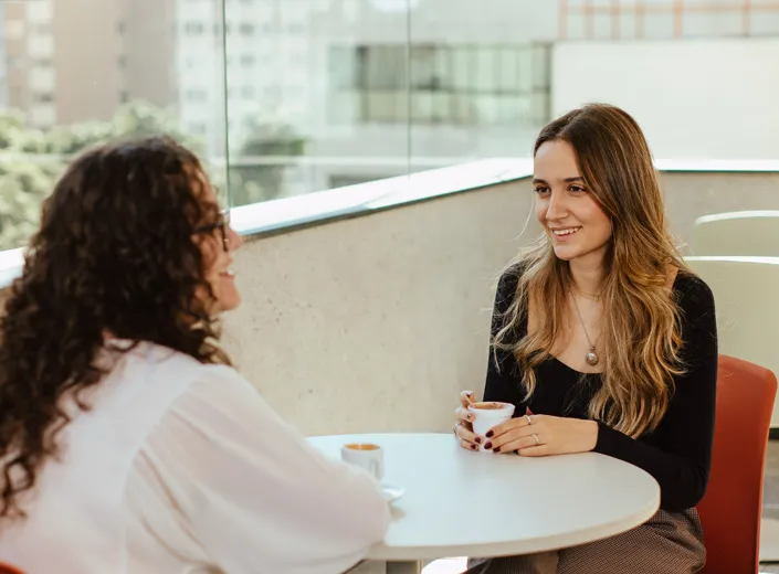 duas alunas sentadas à mesa conversando