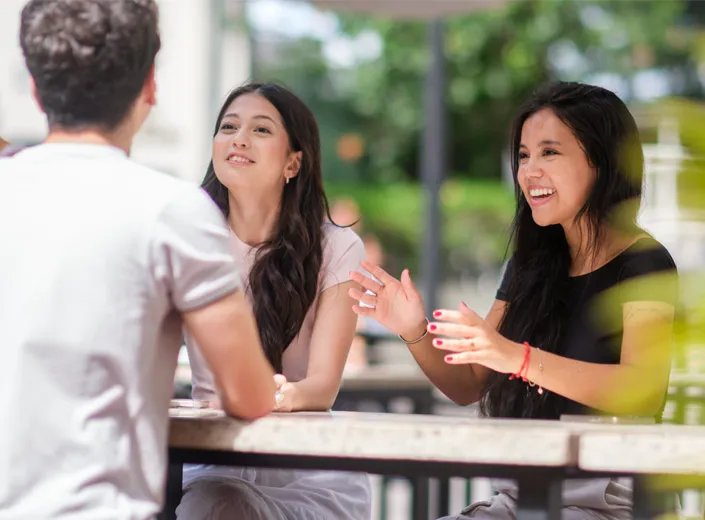 Alunos conversando ao ar livre numa mesa
