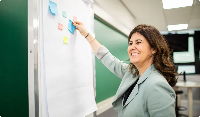 Professora sorridente organizando postit em um quadro