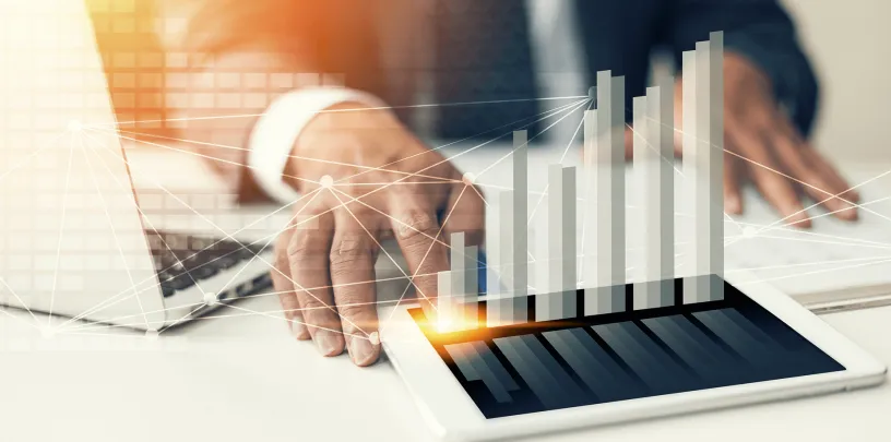 pessoa mexendo com um tablet e gráficos econômicos