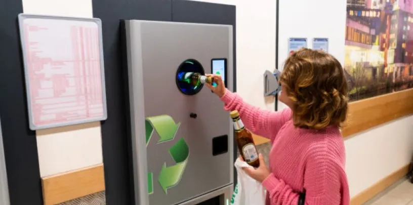 mulher colocando garrafas numa máquina de reciclagem