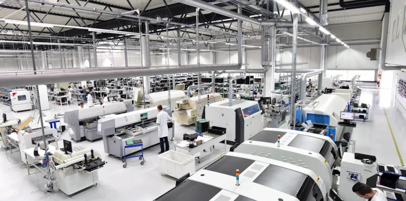 Linha de produção industrial com máquinas automatizadas e técnicos trabalhando em fábrica moderna de eletrônicos