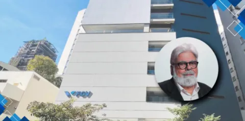 Fachada de um prédio moderno da FGV vista de baixo, com paredes claras, janelas e o logotipo da instituição visível. À direita, há um retrato circular sobreposto de uma pessoa com barba e óculos, em um banner com elementos gráficos em tons de azul.