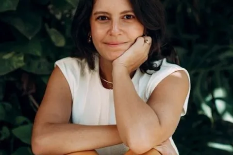 Mulher sentada sorrindo.